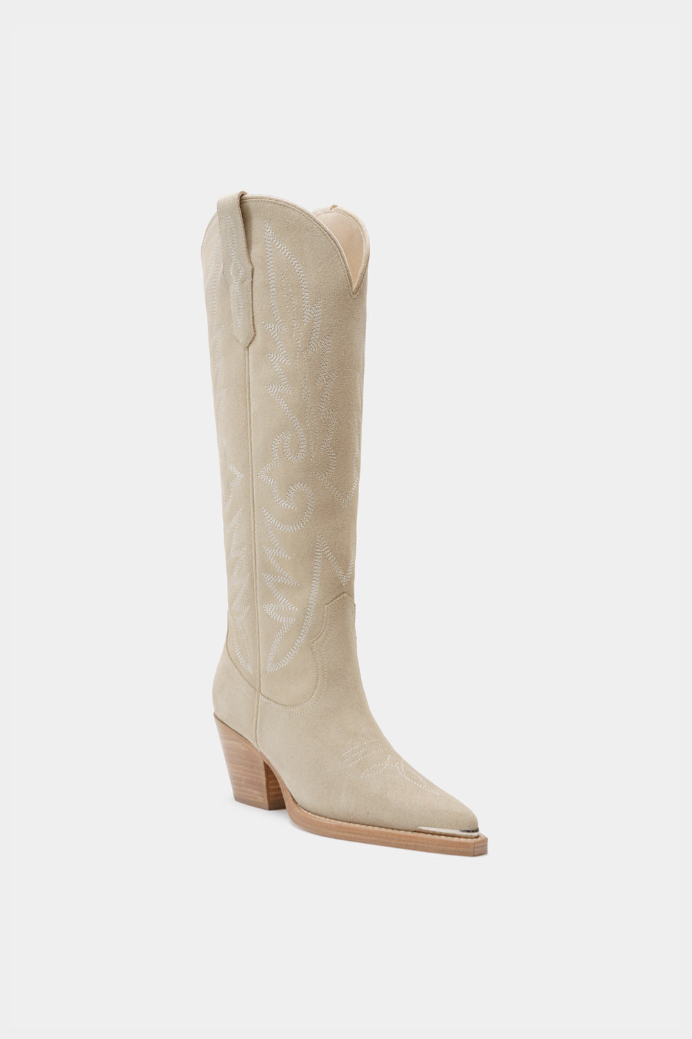 Bota western alta de mujer en gamuza color natural, con bordados elegantes y puntera metálica. Un diseño artesanal de Dante que fusiona tradición y modernidad para crear un ícono de estilo atemporal. Ideal para elevar cualquier look con sofisticación y carácter.