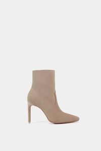 Bota beige de tacón alto tipo stiletto con corte ajustado al tobillo y punta afilada en un material tipo gamuza