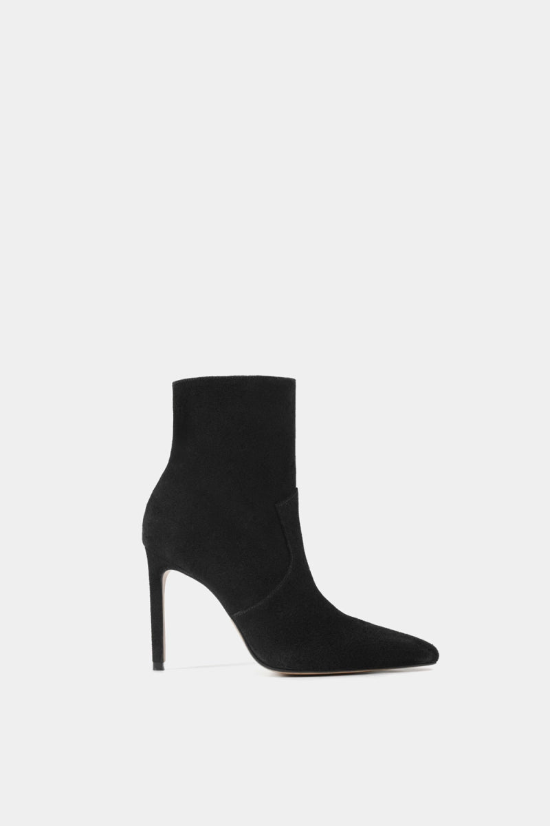 Bota negra de tacón alto tipo stiletto con corte ajustado al tobillo y punta afilada en un material tipo gamuza