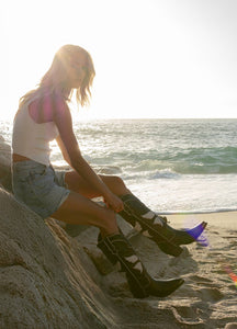 chica con botas de mariposa de mujer en la playa con shorts